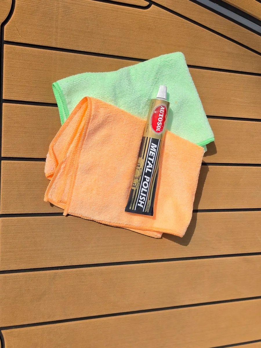 A tube of Autosol metal polish beside two folded microfibre cloths